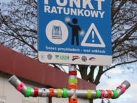 Fotografia przedstawia odblaskowy punkt ratunkowy. Na specjalnym stelażu przyczepione są opaski odblaskowe.